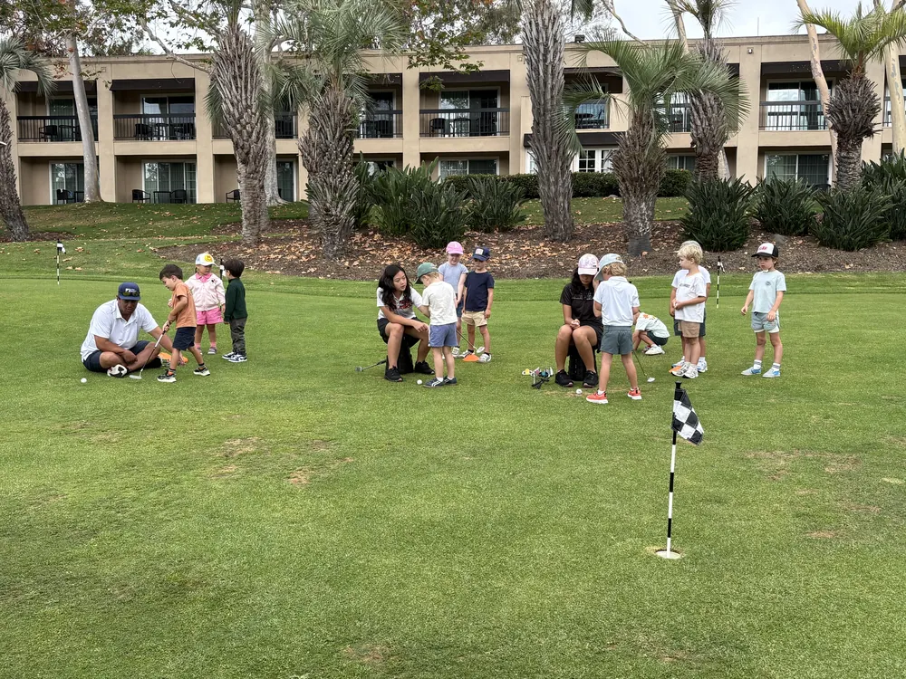 Young players putting on the practice green with a coach