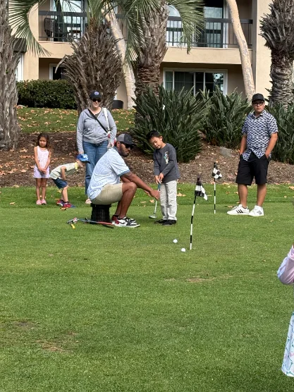 A coach helping a young player line up a shot while family members watch