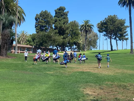 Young players walking the fairway carrying golf bags